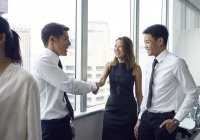 Молоді азіатські бізнесмени тремтять руками в сучасному офісі — стокове фото