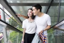 Young attractive asian couple together with shopping bags in mall — Stock Photo
