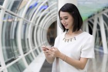 Jeune attrayant asiatique femme en utilisant smartphone — Photo de stock