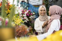 Damas musulmanas jóvenes comprando flores . - foto de stock