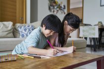 Felice giovane famiglia asiatica insieme disegno a casa — Foto stock
