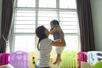 Азіатська мати носить свою дитину в ігровій кімнаті — стокове фото