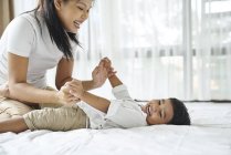 Азіатська мати зв'язується з сином на ліжку — стокове фото