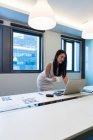 Молода красива азіатська жінка працює з ноутбуком в сучасному офісі — стокове фото