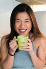 Felice donna cinese bere caffè a casa — Foto stock