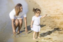 Счастливые молодая мать и дочь проводят время вместе на пляже — стоковое фото