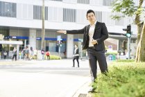 Jovem asiático bem sucedido homem de negócios pegar táxi — Fotografia de Stock