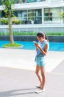 Joven asiático chica usando smartphone en piscina - foto de stock