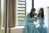 Дві азіатські сестри дивляться на смартфон вдома — стокове фото