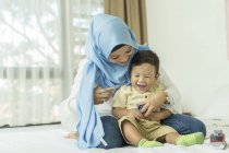 Молодая азиатская мусульманка мать и ребенок веселятся дома — стоковое фото