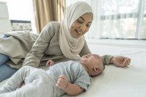Asiático madre hablando a su bebé en casa - foto de stock