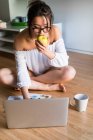 Giovane donna cinese mangiare mela e lavorare sul suo computer portatile — Foto stock