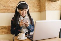 Jovem atraente asiático mulher usando smartphone no café — Fotografia de Stock