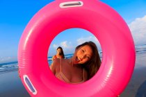 Two young asian female friends are fooling around with their floaties at a beach in Bali. — Stock Photo