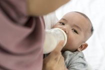 Mutter füttert ihr Baby zu Hause mit Milch — Stockfoto