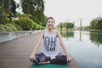 Young sporty asian woman making yoga at pier — Stock Photo