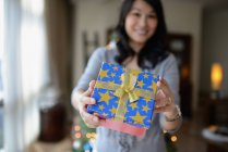 Happy asian woman celebrating Christmas and holding gift at home — Stock Photo