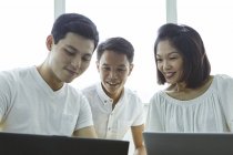 Jeunes gens d'affaires asiatiques travaillant avec des ordinateurs portables au bureau moderne — Photo de stock