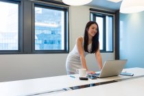 Young beautiful asian woman working with laptop in modern office — Stock Photo