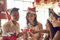 Feliz jovem asiático amigos celebrando Natal juntos no café e torcendo vinho — Fotografia de Stock