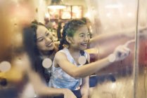 Asian mother and daughter drawing on glass at mall — Stock Photo