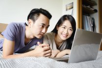 Adulto asiático casal juntos usando laptop em casa — Fotografia de Stock