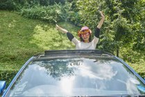 Woman standing outside the sun roof of a car — Stock Photo