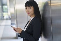 Jovem atraente asiático empresária usando smartphone no escritório moderno — Fotografia de Stock