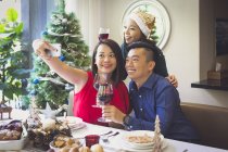 Pareja singapurense disfruta de una cena festiva con un amigo en su hermosa casa durante las vacaciones de Navidad . - foto de stock