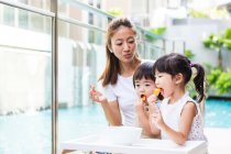 Kids enjoying snack together with their mother. — Stock Photo