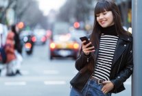 Молодая привлекательная азиатка в городе с помощью смартфона — стоковое фото