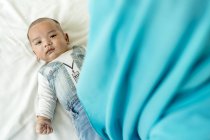 Baby lying down on the bed looking at the camera. — Stock Photo