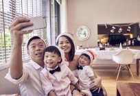 Happy asian family celebrating christmas together and taking selfie at home — Stock Photo