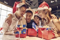 Feliz joven asiático amigos celebrando la Navidad juntos en la cafetería y compartir regalos - foto de stock