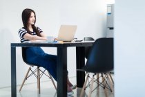 Junge schöne asiatische Frau arbeitet mit Laptop im modernen Büro — Stockfoto