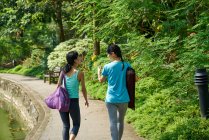 Dos mujeres caminando a su ubicación de Yoga en jardines botánicos, Singapur - foto de stock