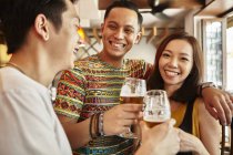 Happy young asian friends together in bar having beer — Stock Photo