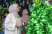 Duas senhoras muçulmanas comprando decorações hari raya . — Fotografia de Stock