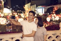Jovem asiático casal passar tempo juntos no tradicional bazar no chinês ano novo e tomando selfie — Fotografia de Stock