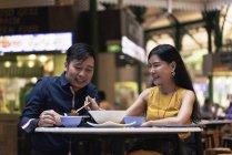 Happy asian young couple together eating in cafe — Stock Photo