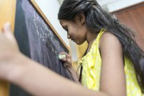 Jeune petite fille asiatique mignonne à l'école à côté du tableau de craie — Photo de stock