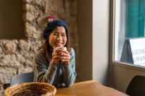Young casual asian girl drinking coffee in cafe — Stock Photo