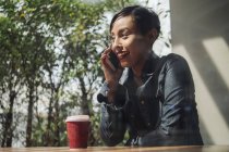 Jovem atraente asiático mulher usando smartphone e tendo café — Fotografia de Stock