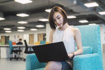 Успішна бізнес-леді використовує ноутбук в сучасному офісі — стокове фото
