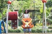 Lindo adorable asiático niña en parque infantil con madre - foto de stock