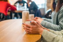 Cropped image of young casual girls drinking coffee in cafe — Stock Photo