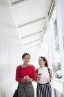 Young asian female friends together walking with coffee — Stock Photo