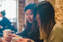 Junge lässige asiatische Mädchen trinken Kaffee im Café — Stockfoto