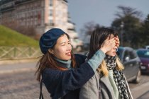 Young casual asian girls, one closing eyes to another — Stock Photo