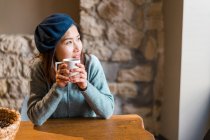 Молодая случайная азиатская девушка пьет кофе в кафе — стоковое фото